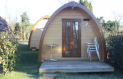 Het Megapod VIP tiny house op Camping De Grienduil in Nederland met terras, stoelen en een tafel.