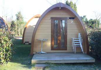 Træhytte Megapod VIP på Camping De Grienduil, Holland, med terrasse, stole og bord i forgrunden.