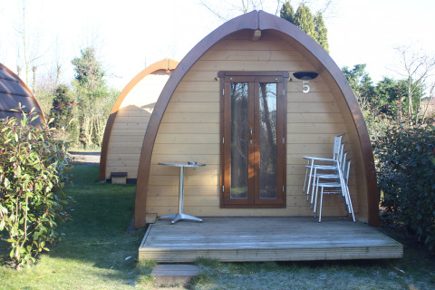 La tiny house Megapod VIP al Camping De Grienduil nei Paesi Bassi, con terrazza, sedie e tavolo.