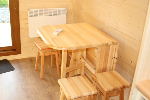 Lichte houten tafel met vier krukken in The Megapod VIP tiny house op Camping De Grienduil, Nederland.