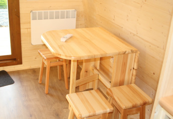Tavolo in legno chiaro con quattro sgabelli abbinati nel Megapod VIP di Camping De Grienduil, Paesi Bassi.