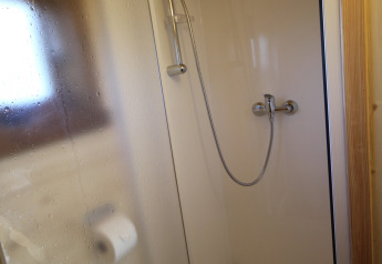 Compact shower cubicle with glass sliding door and toilet paper holder in The Megapod VIP, Camping De Grienduil.