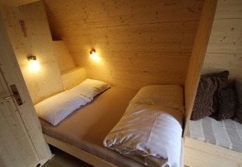 Cozy bedroom with double bed and wood walls inside The Megapod VIP at Camping De Grienduil, Netherlands.