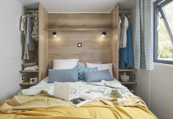Camera da letto accogliente e luminosa in una tiny house con cuscini morbidi e arredo moderno in legno.