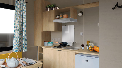 Kompakte Küche im Tiny House 11 von Camping De Grienduil, Niederlande, mit Holzschränken und Mini-Kühlschrank.