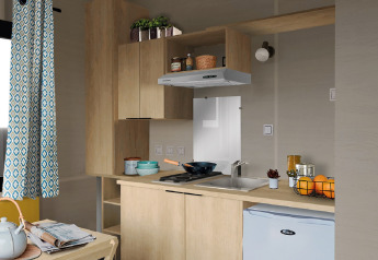 Modern tiny kitchen in Tiny House 11 at Camping De Grienduil, Netherlands, with wood cabinets and fridge.