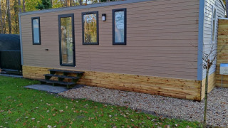 Alojamiento moderno de Luxe Homes en Bospark De Brenkberg, Países Bajos, con césped y árboles alrededor.
