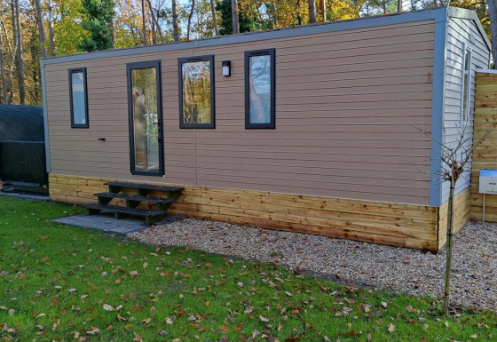 Ein modernes Luxushaus von Luxe Homes im Bospark De Brenkberg, Niederlande, vor Bäumen und Rasen.
