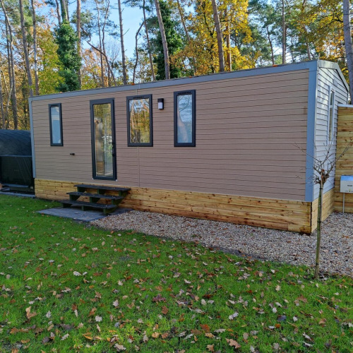 Modern Luxe Homes lodge at Bospark De Brenkberg, Netherlands, surrounded by green grass and trees.