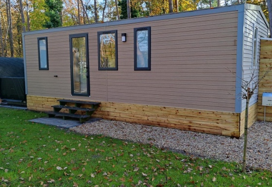 Alojamiento moderno de Luxe Homes en Bospark De Brenkberg, Países Bajos, con césped y árboles alrededor.