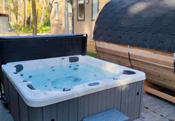 Bubbelbad en ton-sauna buiten bij een lodge van Luxe Homes, Bospark De Brenkberg, Nederland, in het bos.