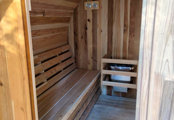 Intérieur d’un sauna en bois à Luxe Homes, Bospark De Brenkberg, Pays-Bas, avec banc et poêle.