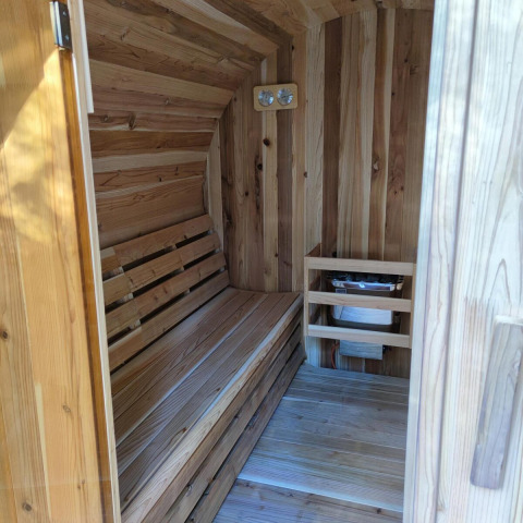 Interior de una sauna de madera en Luxe Homes, Bospark De Brenkberg, Países Bajos, con banco y calentador.