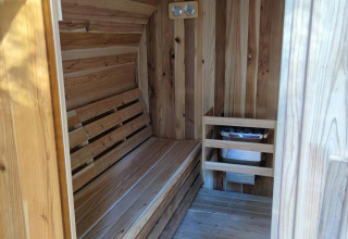 Innenansicht einer Holzsauna im Luxe Homes in Bospark De Brenkberg, Niederlande, mit Bank und Ofen.