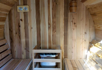 Binnenaanzicht van een houten sauna met twee banken en een kachel bij Luxe Homes op Bospark De Brenkberg.