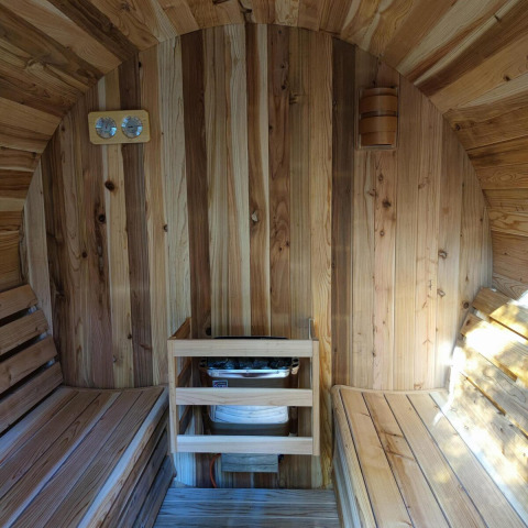 Vista interior de una sauna de madera con dos bancos y calentador en Luxe Homes en Bospark De Brenkberg.