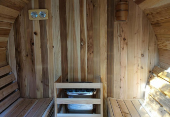 Vista interior de una sauna de madera con dos bancos y calentador en Luxe Homes en Bospark De Brenkberg.