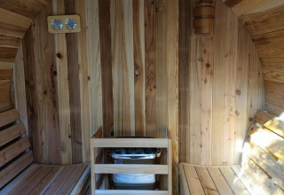 Vista interior de una sauna de madera con dos bancos y calentador en Luxe Homes en Bospark De Brenkberg.