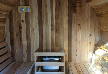 Vista interior de una sauna de madera con dos bancos y calentador en Luxe Homes en Bospark De Brenkberg.