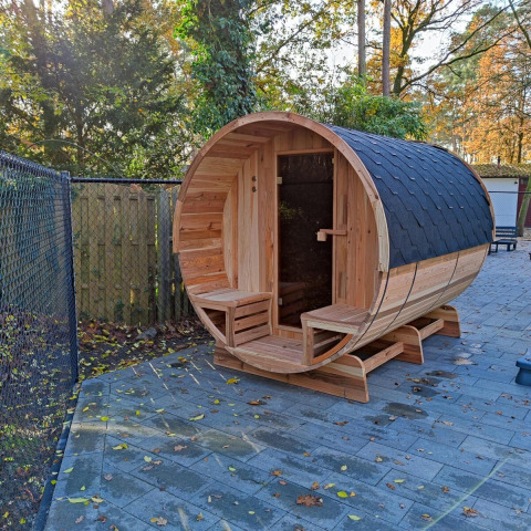 Sauna de barril de madera al aire libre en Luxe Homes, Bospark De Brenkberg, Países Bajos, rodeada de árboles.