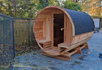 Udendørs tøndesauna i træ ved Luxe Homes, Bospark De Brenkberg, Nederlandene, omkranset af natur.