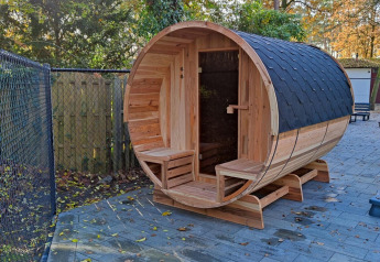 Fasssauna aus Holz im Außenbereich bei Luxe Homes im Bospark De Brenkberg, Niederlande, Waldumgebung.