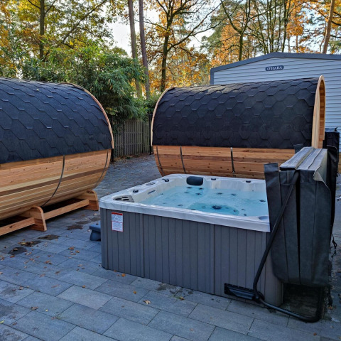 Zona de spa al aire libre con dos saunas de barril y jacuzzi en Luxe Homes, Bospark De Brenkberg, Países Bajos.
