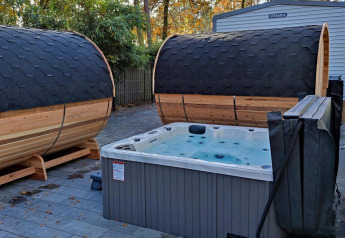 Outdoor spa area with two barrel saunas and a hot tub at Luxe Homes, Bospark De Brenkberg, Netherlands.