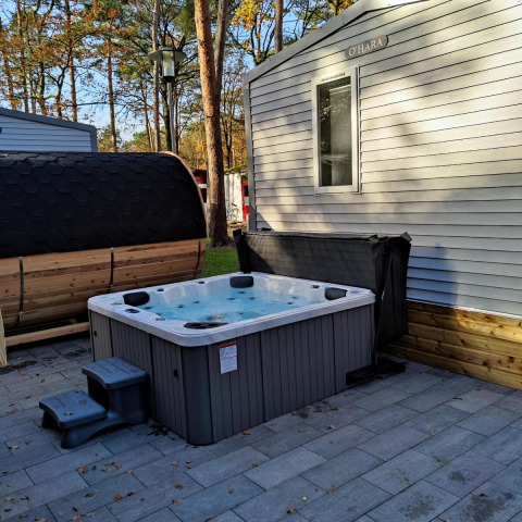 Jacuzzi y sauna al aire libre junto a una cabaña O'HARA en Bospark De Brenkberg, Países Bajos.