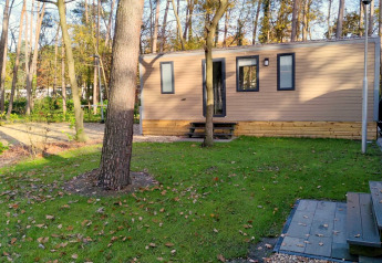 Modernes Lodgehaus von Luxe Homes bei Bospark De Brenkberg, Niederlande, umgeben von Bäumen und Natur.