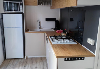 Modern kitchenette with wood countertop, gas stove, microwave, and fridge at Luxe Homes in the Netherlands.