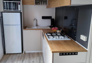 Moderne tekøkken med træbordplade, gaskomfur, vask, mikrobølgeovn og køleskab på Luxe Homes i Holland.