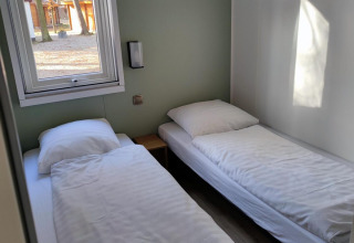 Dos camas individuales con sábanas blancas en una habitación luminosa en Luxe Homes, Bospark De Brenkberg, Países Bajos.