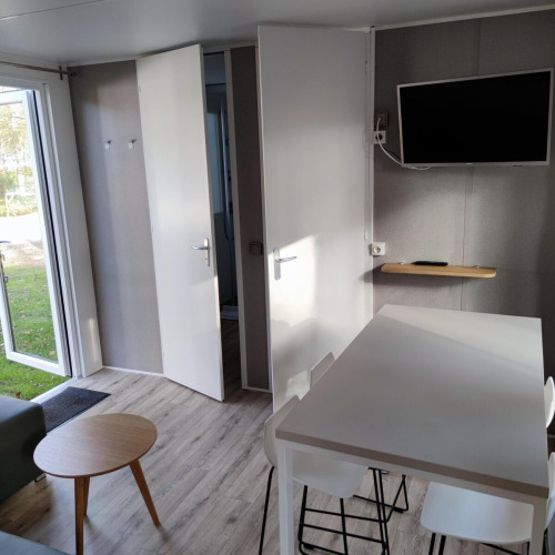 Interior view of a modern lodge at Luxe Homes, Bospark De Brenkberg, with table, chairs, and a TV on the wall.
