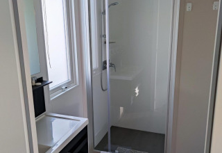 Baño moderno con cabina de ducha, lavabo, espejo y toallas en Luxe Homes, Bospark De Brenkberg, Países Bajos.