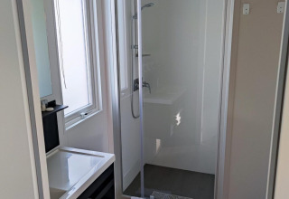 Modernes Badezimmer mit Dusche, Waschbecken, Spiegel und Handtüchern in Luxe Homes, Bospark De Brenkberg, Niederlande.