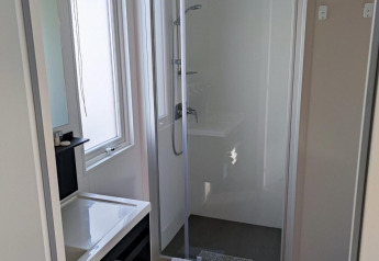 Moderne badkamer met douchecabine, wastafel, spiegel en handdoeken in Luxe Homes, Bospark De Brenkberg, Nederland.