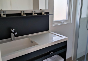 Baño moderno en Luxe Homes en Bospark De Brenkberg, Países Bajos, con lavamanos, toallas y ducha acristalada.