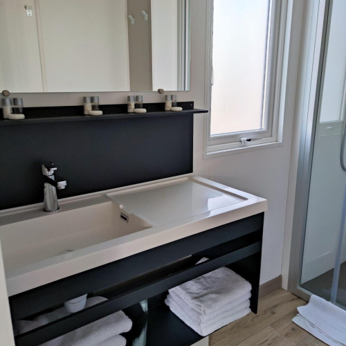 Modern bathroom at Luxe Homes, Bospark De Brenkberg, Netherlands with towels, sink, and a glass shower.