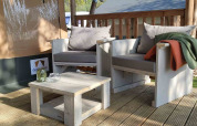Outdoor seating with light wooden chairs and cushions at a glamping tent at Camping Batenstein, Netherlands.