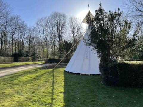 Un tipi au parc de vacances Buytenplaets Abelen à Flevoland, Pays-Bas, entouré d’arbres et de pelouse verte.