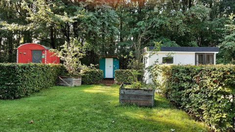 Bunte kleine Hütten mit Hecken und Bäumen im Buytenplaets Suydersee Ferienpark in Flevoland, Niederlande.