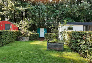 Bunte kleine Hütten mit Hecken und Bäumen im Buytenplaets Suydersee Ferienpark in Flevoland, Niederlande.