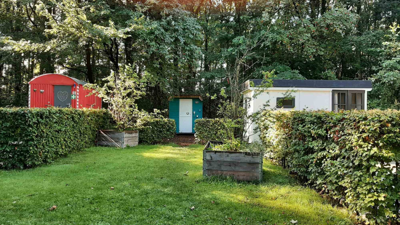 Bunte kleine Hütten mit Hecken und Bäumen im Buytenplaets Suydersee Ferienpark in Flevoland, Niederlande.