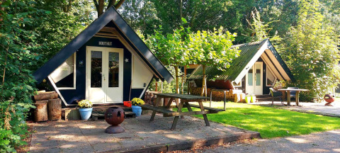 Twee gezellige A-frame hutten met picknicktafels in Buytenplaets Suydersee, vakantiepark Flevoland, Nederland.