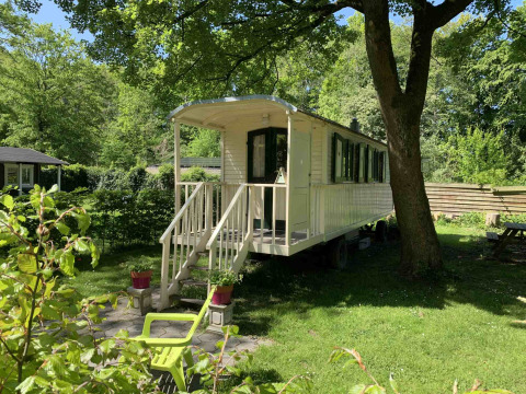 Foto van een gezellige woonwagen onder de bomen bij Buytenplaets Suydersee vakantiepark in Flevoland, Nederland.