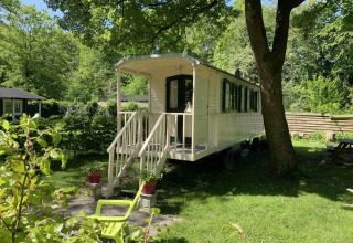 Foto van een gezellige woonwagen onder de bomen bij Buytenplaets Suydersee vakantiepark in Flevoland, Nederland.