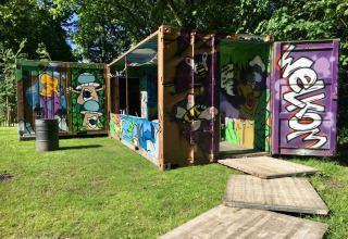 Bunte Graffiti schmücken einen Container im Grünen im Buytenplaets Suydersee Ferienpark, Flevoland.