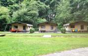 Tres tiendas safari con sillas de colores al aire libre en Buytenplaets Suydersee, Países Bajos, junto a un bosque.