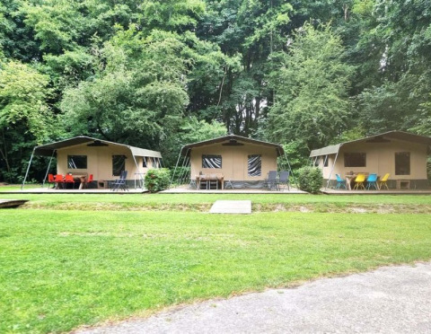 Drei Safarizelte mit bunten Stühlen vor einem Wald im Buytenplaets Suydersee, Niederlande.